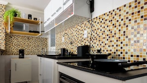 A modern kitchen with white cabinets, a black stove, and a tiled backsplash. - ApartDeck Fantasy Island (Rio de Janeiro)