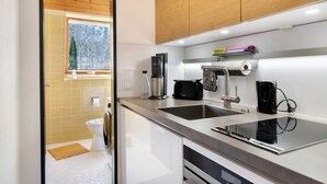 A modern kitchen with a built-in dishwasher, a coffee maker, and a kettle.