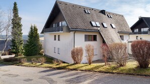 A modern house with a sloped roof, a small front porch, and a well-maintained lawn.