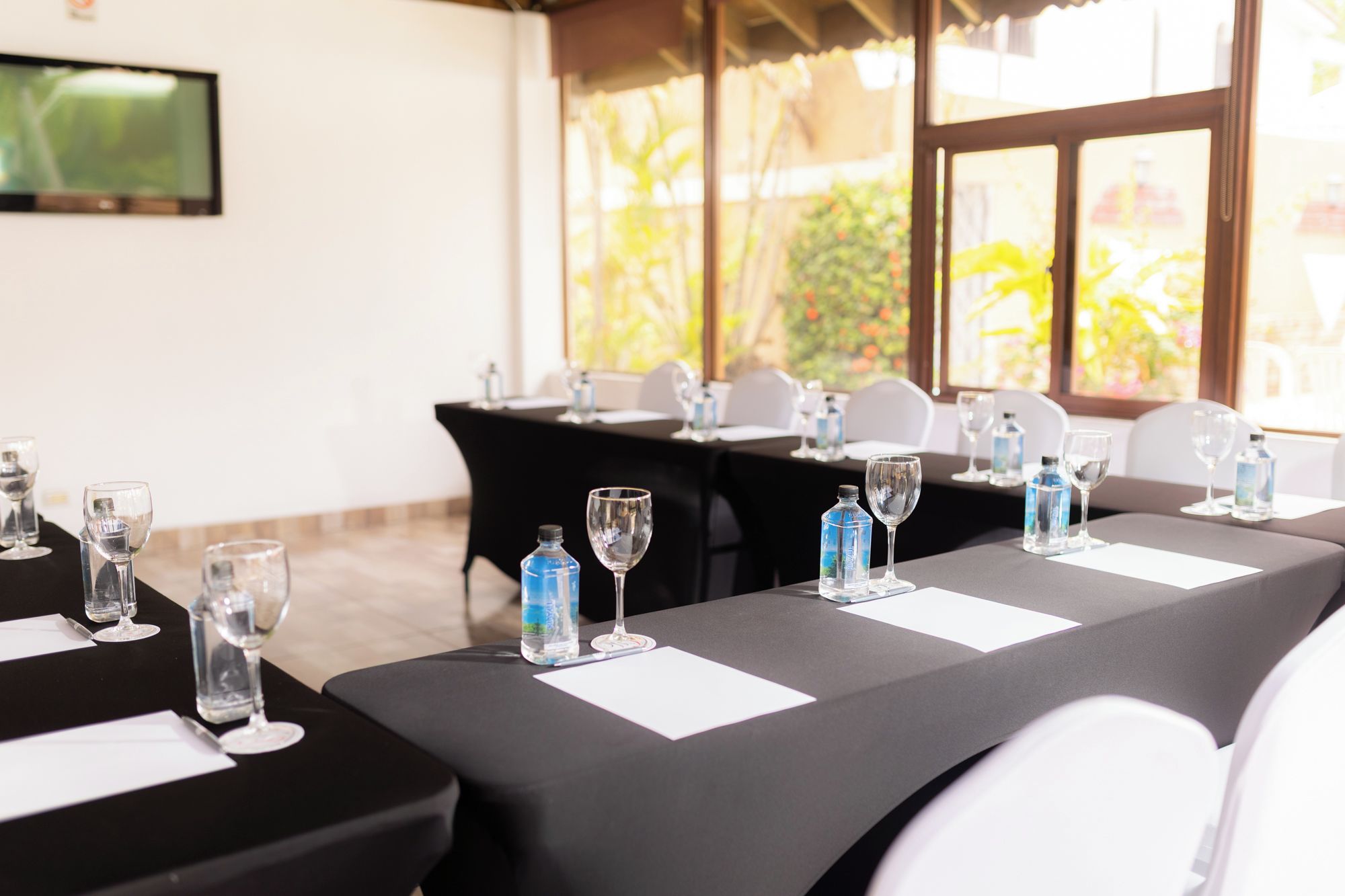 A conference room with tables set for a meeting, equipped with water bottles and glasses.