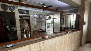 Un espace d’accueil doté d’un comptoir en marbre, de ventilateurs de plafond et d’un grand miroir.