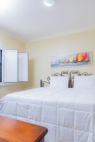 Una habitación con una cama, un cuadro y una ventana.