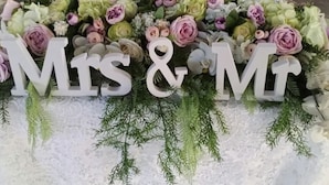 Une table dressée avec un centre de table floral, des lettres « M » et « M », et des verres à vin.
