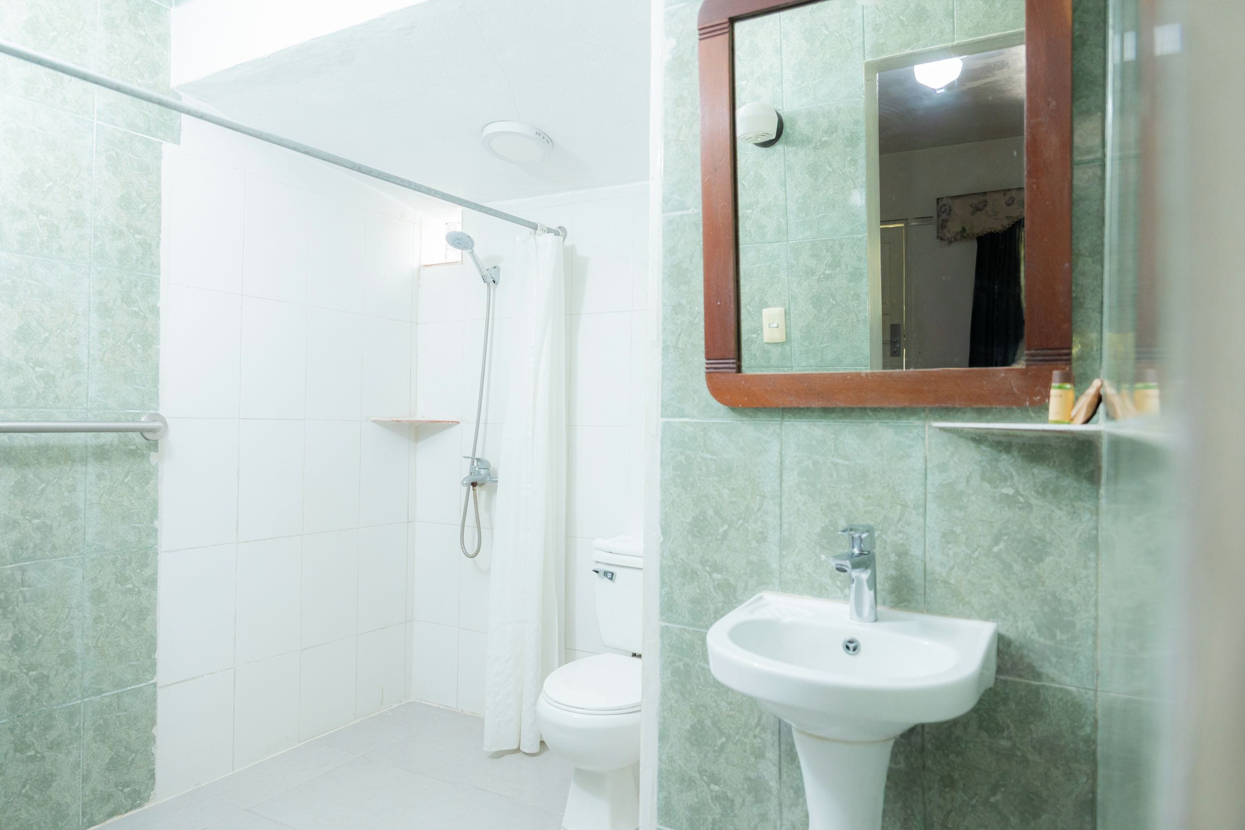 Een badkamer met douche, toilet en wastafel.