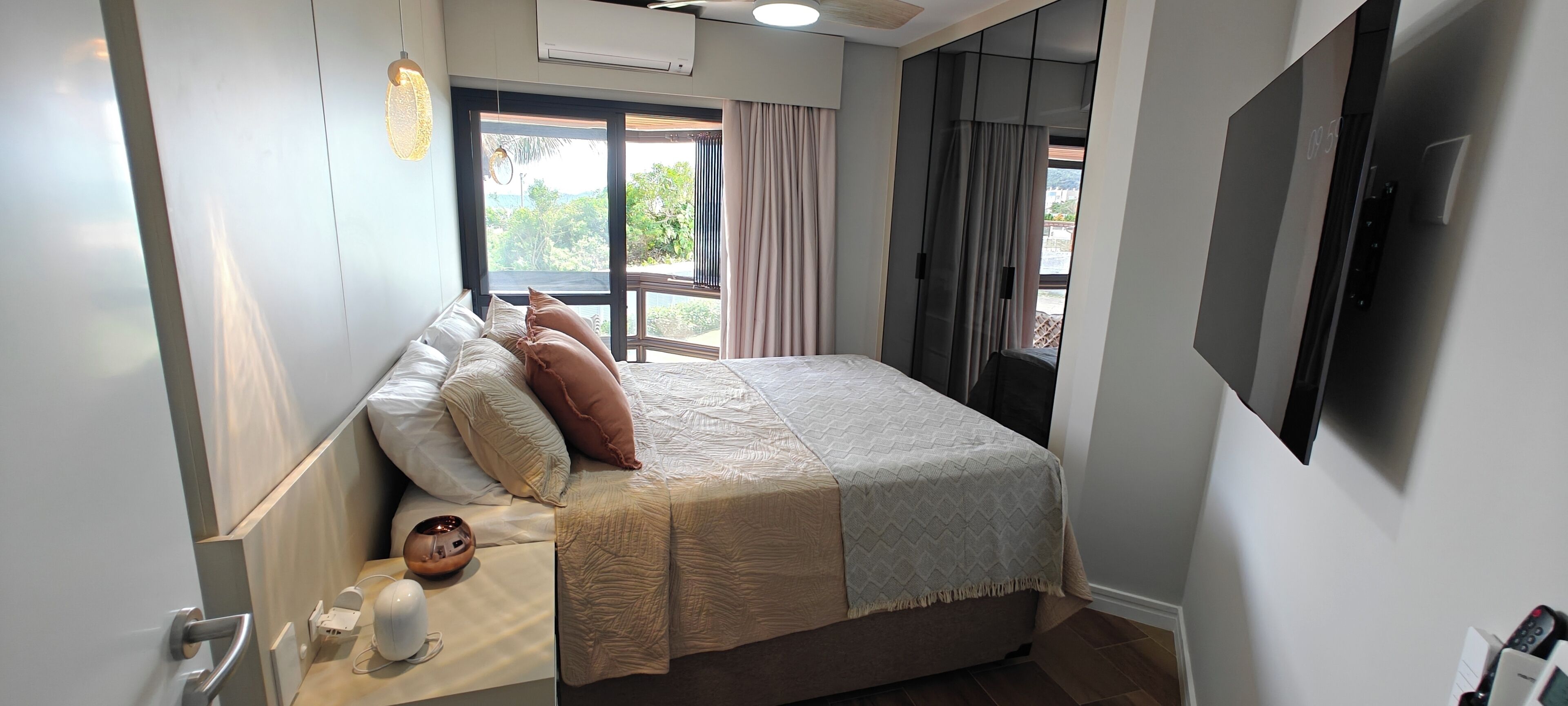 Une chambre à coucher moderne avec un grand lit, un téléviseur à écran plat, une fenêtre avec des rideaux et un ventilateur de plafond.
