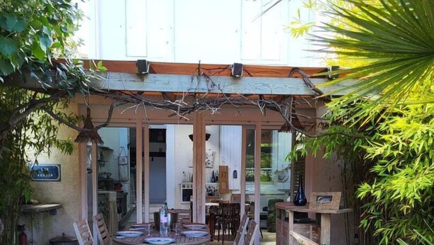 Un'area patio all'aperto con pavimento in pietra, arredi in legno e una struttura a pergola.