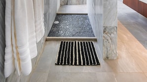 A modern bathroom with marble walls, a bathtub, and a shower area. - Villa Deluxe SlowLiving Tulum CountryClub Golf PGA (Gran Bahía Príncipe)
