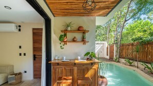 A wooden bar with stools, a pool, and potted plants. - •LUMA SwimUp Pools, Garden & Quiet Living | Tulum (Tulum)
