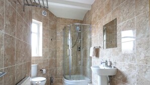 A bathroom with a glass-enclosed shower, a toilet, a sink, and a mirror. - 5 bedroom house, free parking, near football, sleeps 8 (Liverpool)