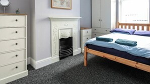 A bedroom with a bed, dresser, wardrobe, and a fireplace. - 5 bedroom house, free parking, near football, sleeps 8 (Liverpool)