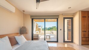 A bedroom with a bed, a ceiling fan, a large sliding glass door leading to an outdoor patio with a table and chairs. - •|AMARU Penthouse | Private Rooftop & Quiet Living (Tulum)