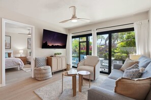 A spacious living room with a large window, a ceiling fan, a sofa, a coffee table, and a cabinet. - B-114 -Totally Remodeled With Walk Out Lanai (Naples)