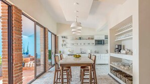 Una cucina moderna con mobili bianchi, una grande isola e un'area pranzo con un tavolo e sedie in legno.