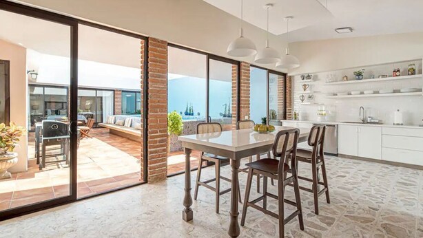 Una cucina moderna con un grande tavolo da pranzo, mobili bianchi e vista sull'esterno.