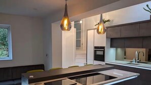 A modern kitchen with a central island, pendant lighting, and a built-in oven.