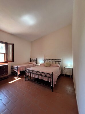 Ein Schlafzimmer mit zwei Betten, einem Schminktisch, einem Nachttisch und einem Fenster mit Vorhängen.