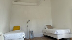 A small, well-lit room with two single beds, a desk, and a chair. - Luxembourg Montparnasse (Paris)