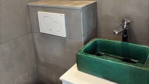 A bathroom with a toilet, a green sink, and a white cabinet. - Luxembourg Montparnasse (Paris)