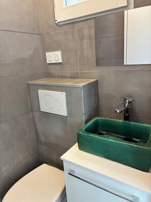 A bathroom with a toilet, a green sink, and a white cabinet. - Luxembourg Montparnasse (Paris)