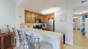 Una cocina moderna con armarios de madera, electrodomésticos de acero inoxidable y una zona de bar con sillas.