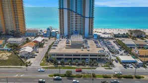 Un hotel costero con varios pisos, estacionamiento y vista al mar.