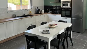 Una cocina moderna con armarios blancos, una mesa de comedor con sillas, un microondas y un refrigerador.