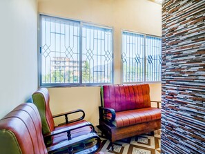 A room with a sofa, a chair, and a patterned wall. - Brahmaputra View Guest House (Chandanpur)