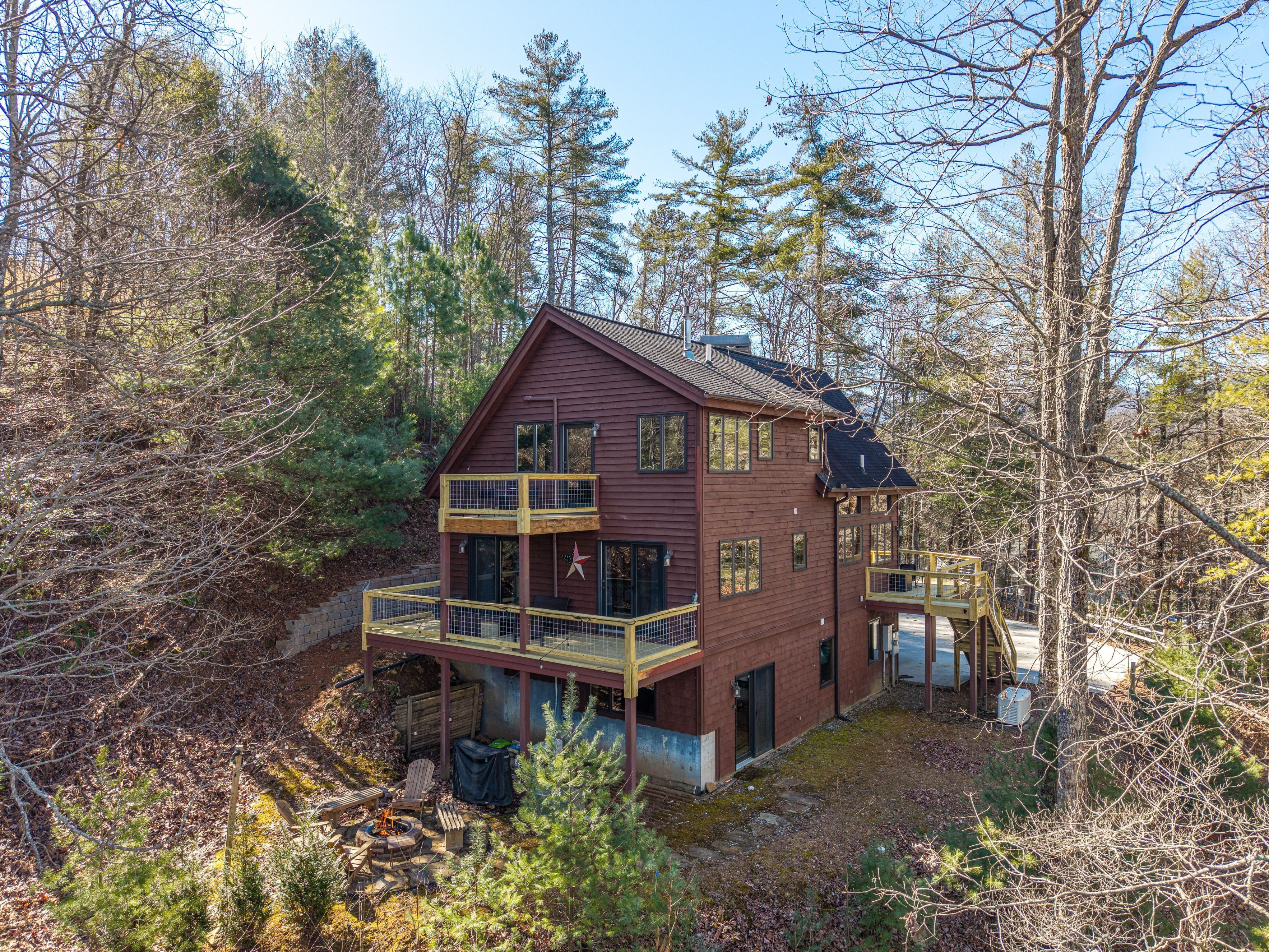 A two-story cabin with a balcony, surrounded by trees.
