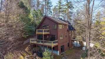 A two-story cabin with a balcony, surrounded by trees.