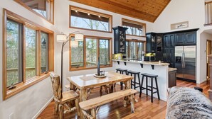 Un'ampia cucina con mobili in legno, un'isola centrale con sgabelli e grandi finestre che offrono vista sull'esterno.