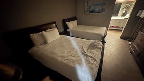 Habitación de hotel con dos camas, cabecero de madera, un cuadro en la pared y vista al baño.