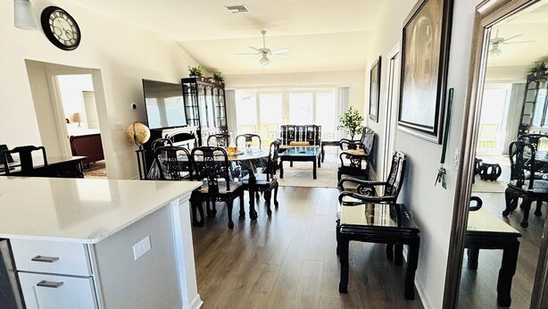 A spacious kitchen with a central island, dining area with multiple chairs, and a large mirror reflecting the room. -  Sun-Filled Brand-New Edenfield Designer Home (Sumterville)
