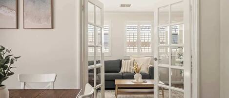 A room with a dining table, chairs, a sofa, a coffee table, and a door leading to another room.