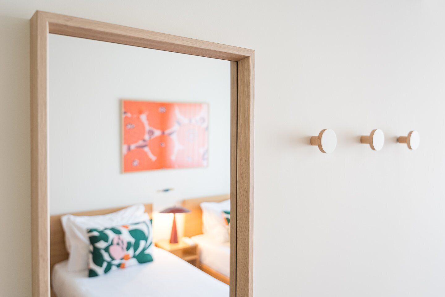 A hotel room with a bed, a nightstand, a lamp, and a wall-mounted artwork.