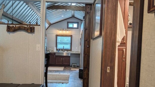 A narrow hallway leading to a kitchen with a TV mounted on the wall.