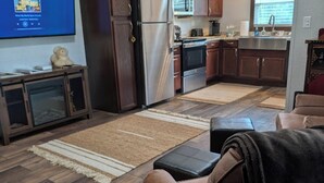 A compact RV interior with a kitchenette, a television, and a sofa.