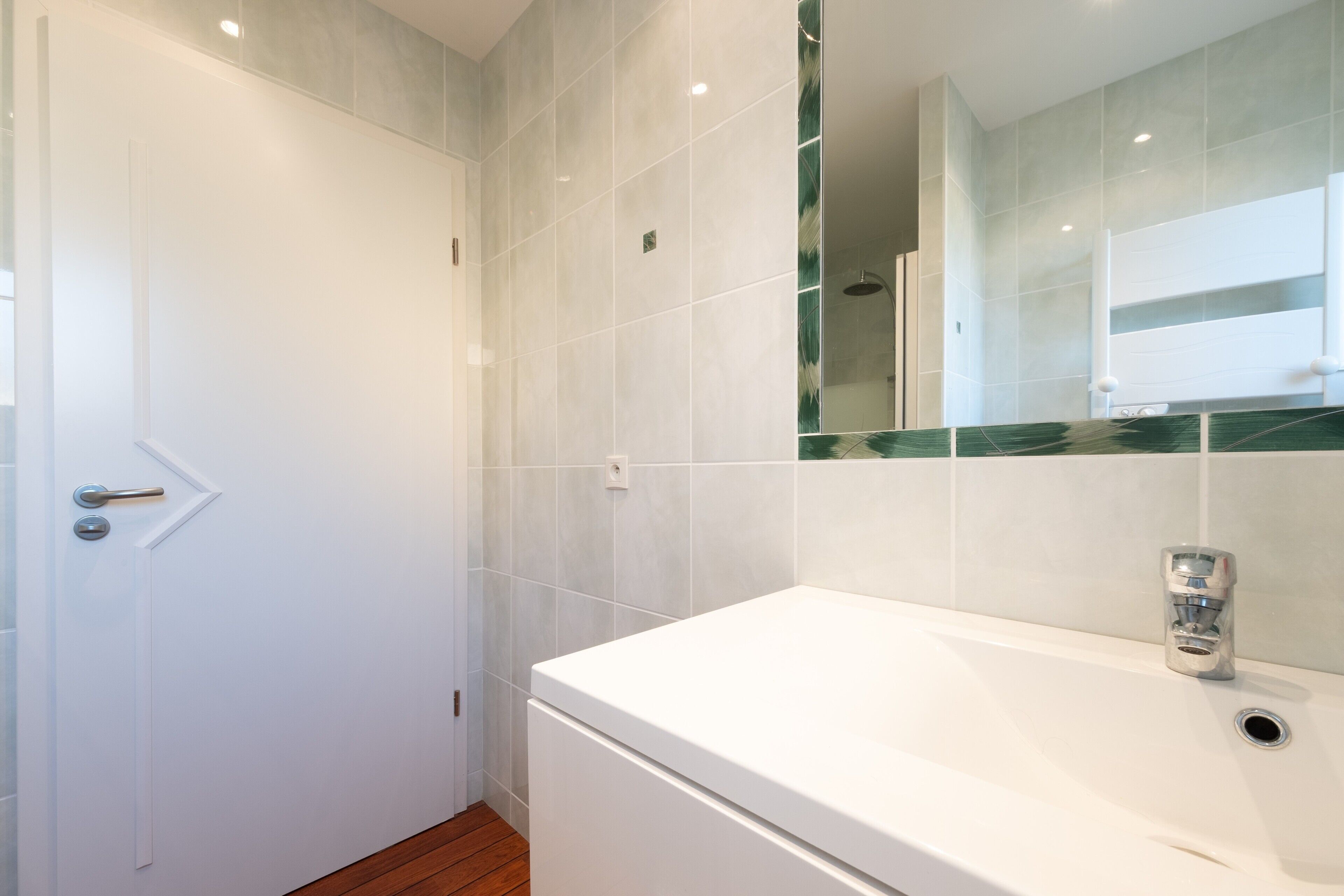 A bathroom with a white bathtub, a door, and tiled walls.