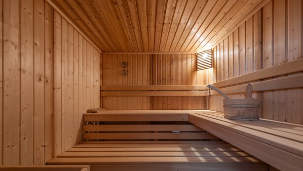 Eine Holzsauna mit Bänken und einem Eimer.