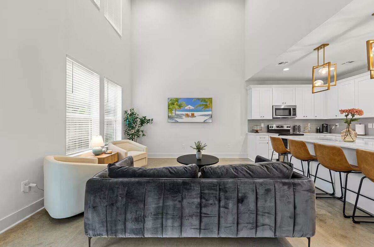 A modern living room with a grey sofa, a small round table, and a painting of a beach scene.