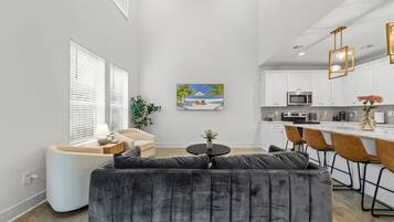 A modern living room with a grey sofa, a small round table, and a painting of a beach scene.