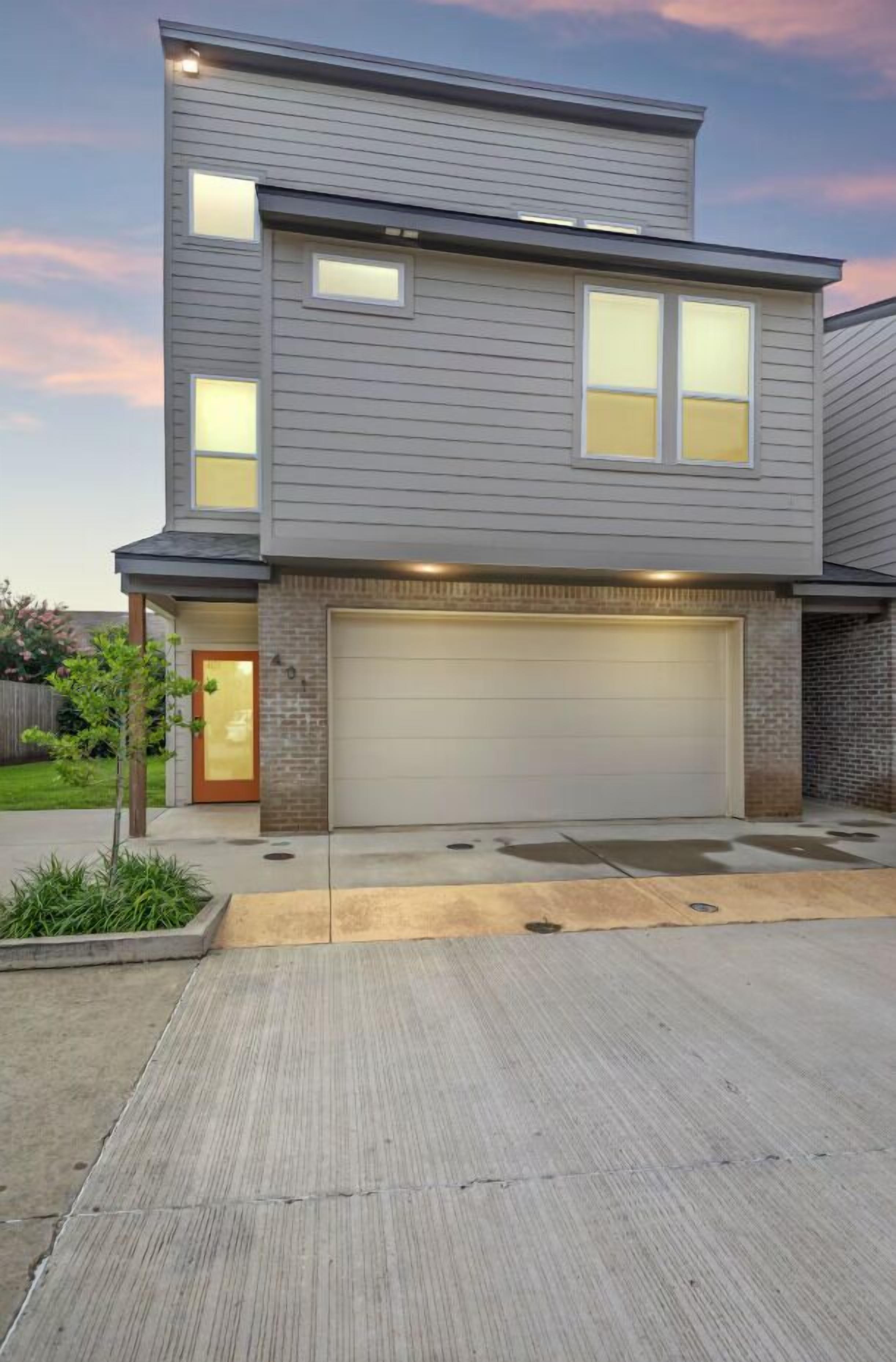 A modern two-story house with a garage, a small front yard, and a driveway.
