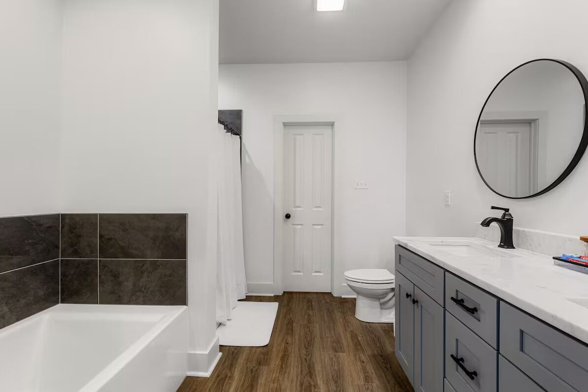 A modern bathroom with a bathtub, a toilet, and a vanity with a mirror.