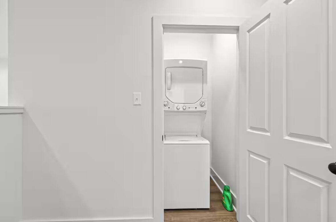 Um corredor estreito com uma porta branca à direita e uma parede branca à esquerda.