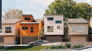 A row of modern townhouses with attached garages, a fire department use sprinkler box, and a parked car. - Enclave 2 Bedroom Luxury Homes (Lafayette)