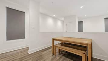 A room with a wooden bench, white walls, and a large window.