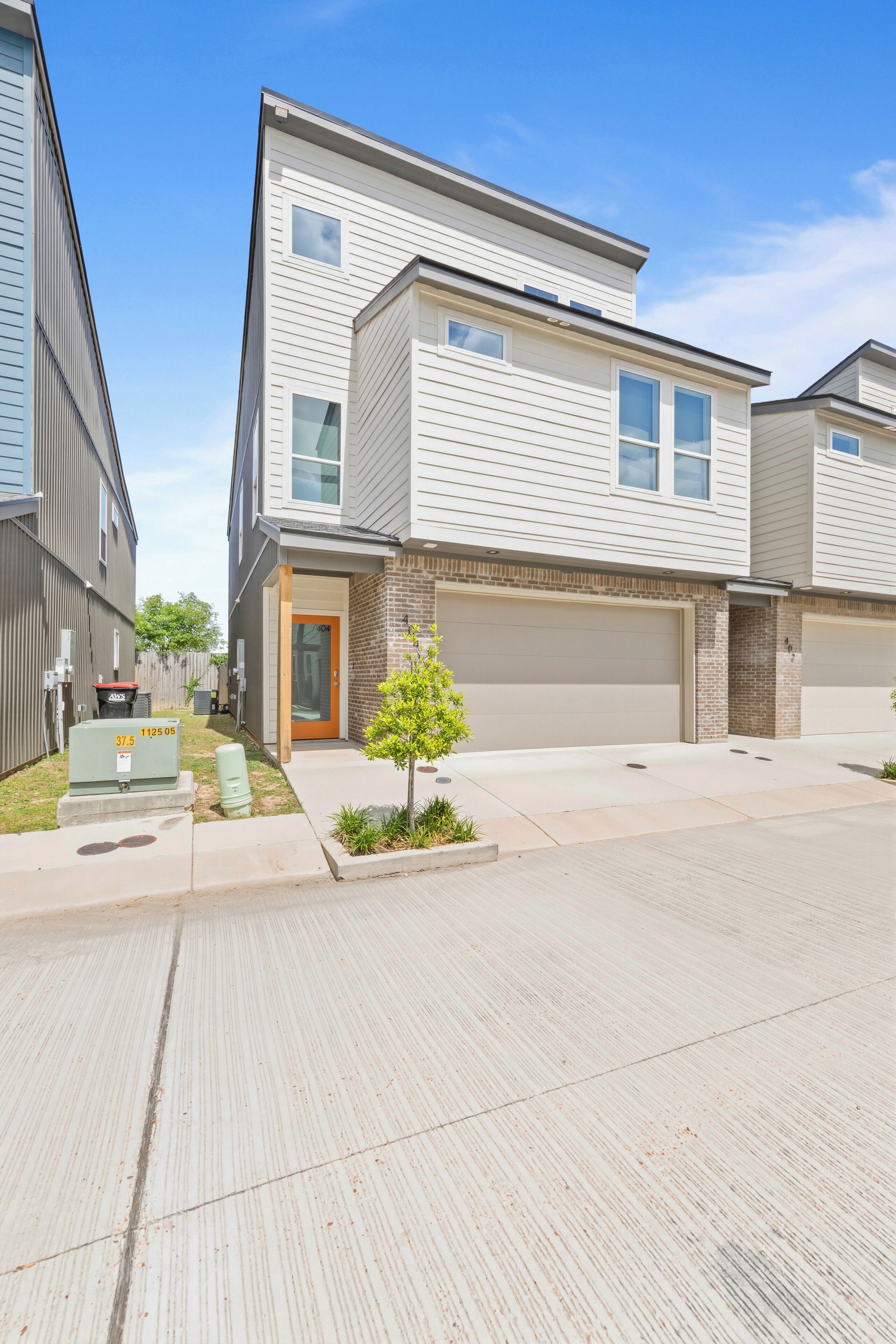 A modern townhouse with a garage, a small front yard, and a mailbox.