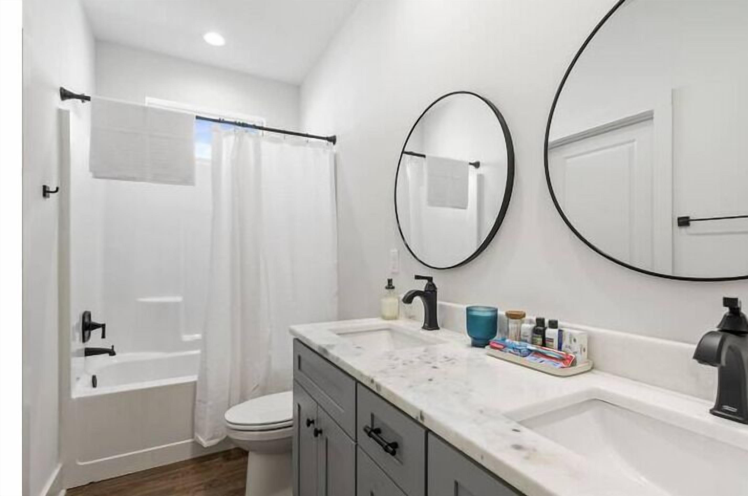 Un baño moderno con bañera, inodoro y tocador con lavamanos y espejos.