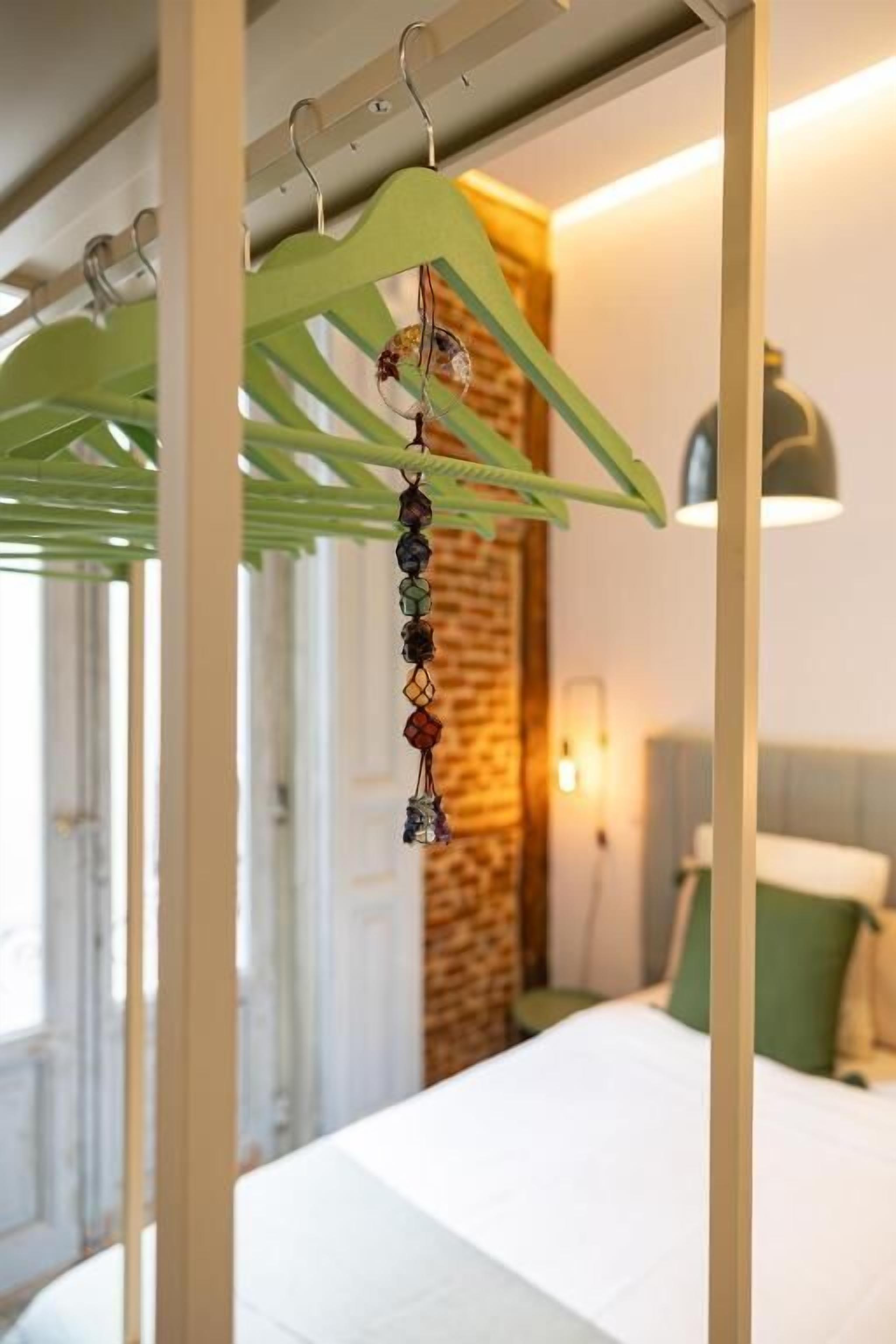 A hotel room with a bed, a hanging decorative item, and a brick wall.