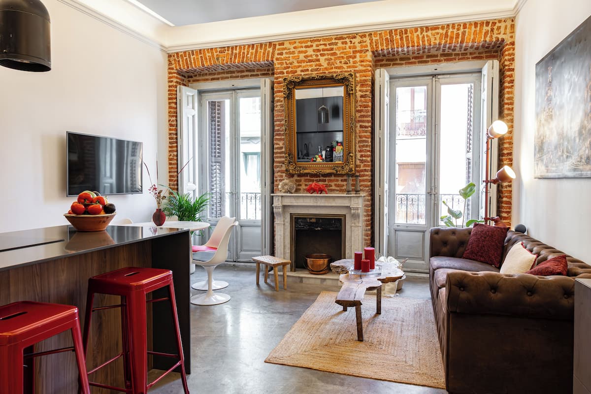 Una sala de estar moderna con chimenea de ladrillo, comedor y cocina con barra.