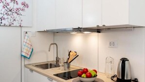 A modern kitchen with a built-in stove, a sink, and a bowl of fruit on the countertop. - Sunny Palace Studio 2 (Dubrovnik)